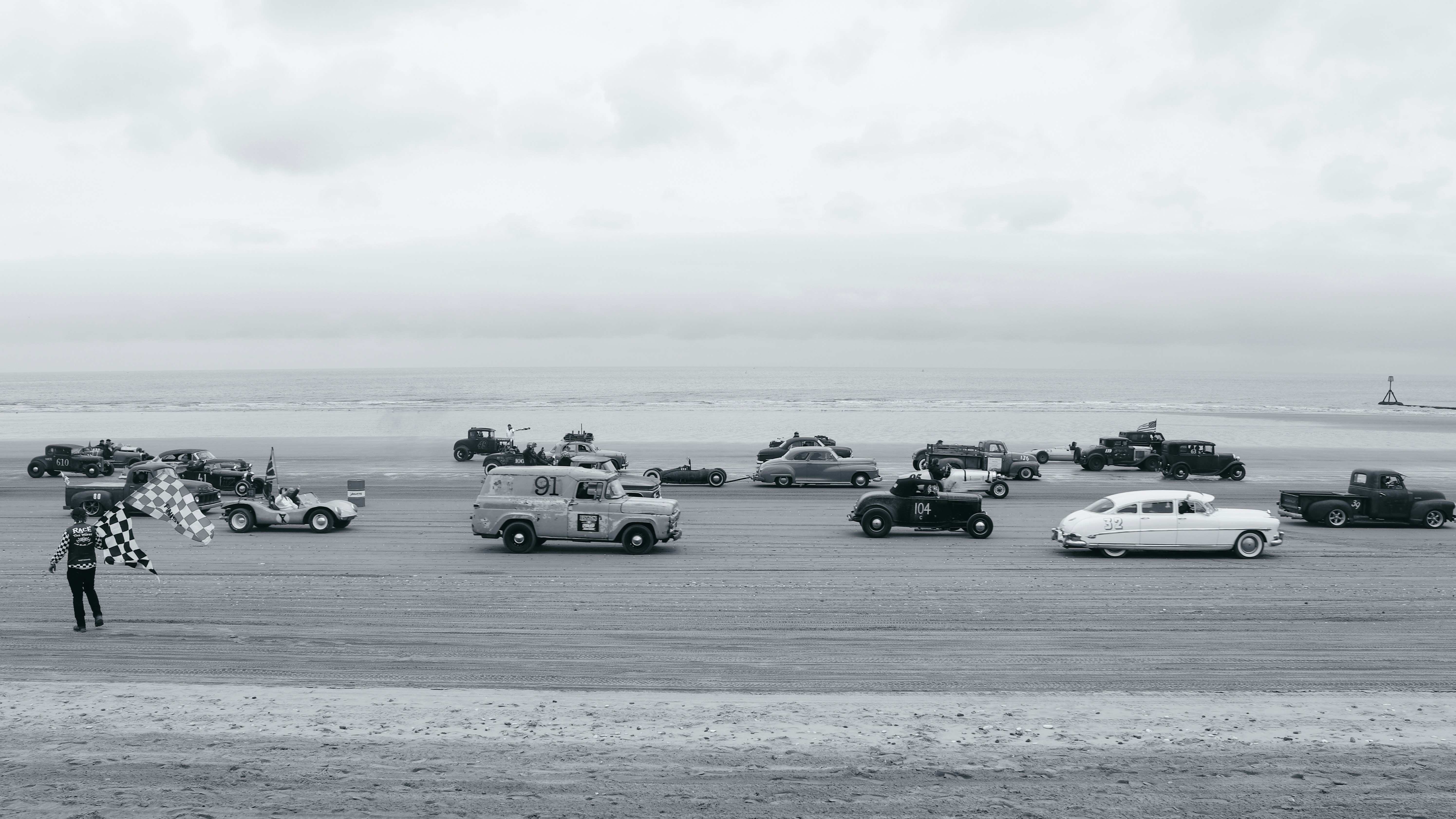 a black and white photo of a person standing in front of a bunch of cars
