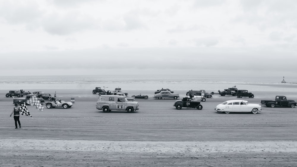a black and white photo of a person standing in front of a bunch of cars