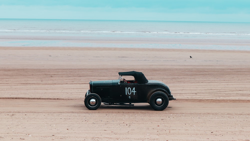 an old car is parked on the beach