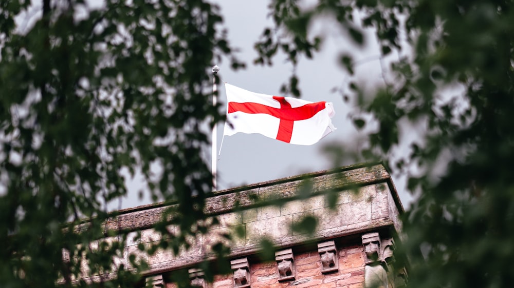 a red and white flag flying on top of a building