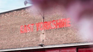A brick wall with large red letters spelling out 'EAST YORKSHIRE'. The sky is partially visible above, and there is a hint of reflection or blur in the foreground.
