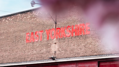 A brick wall with large red letters spelling out 'EAST YORKSHIRE'. The sky is partially visible above, and there is a hint of reflection or blur in the foreground.