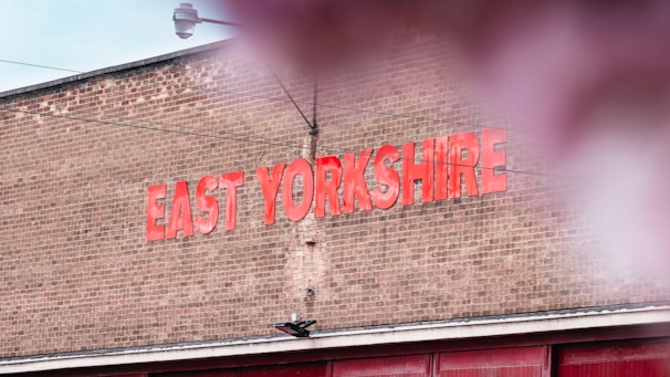A brick wall with large red letters spelling out 'EAST YORKSHIRE'. The sky is partially visible above, and there is a hint of reflection or blur in the foreground.
