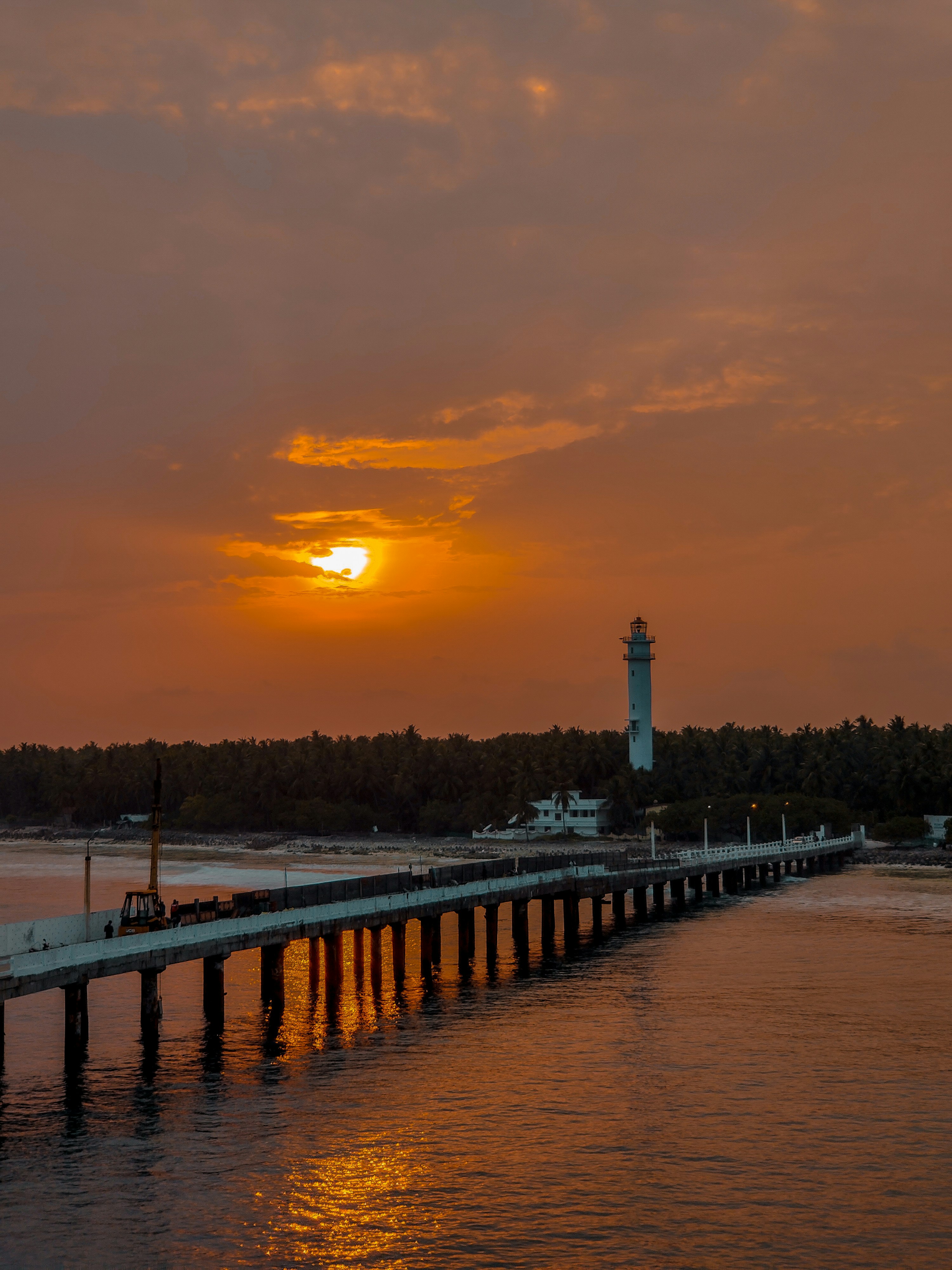 the sun is setting over the water near a pier