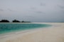 a sandy beach with a small island in the distance
