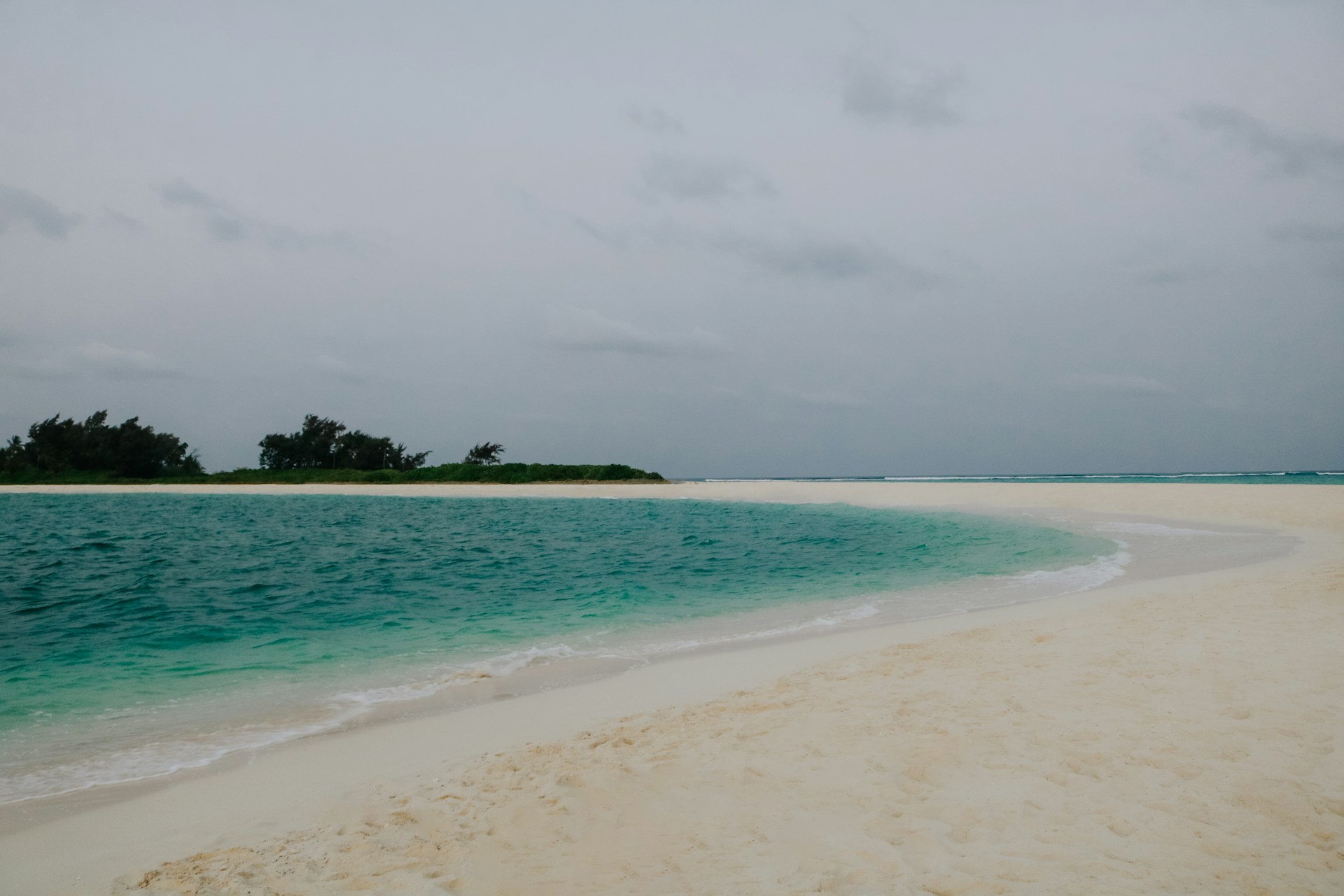 a sandy beach with a small island in the distance