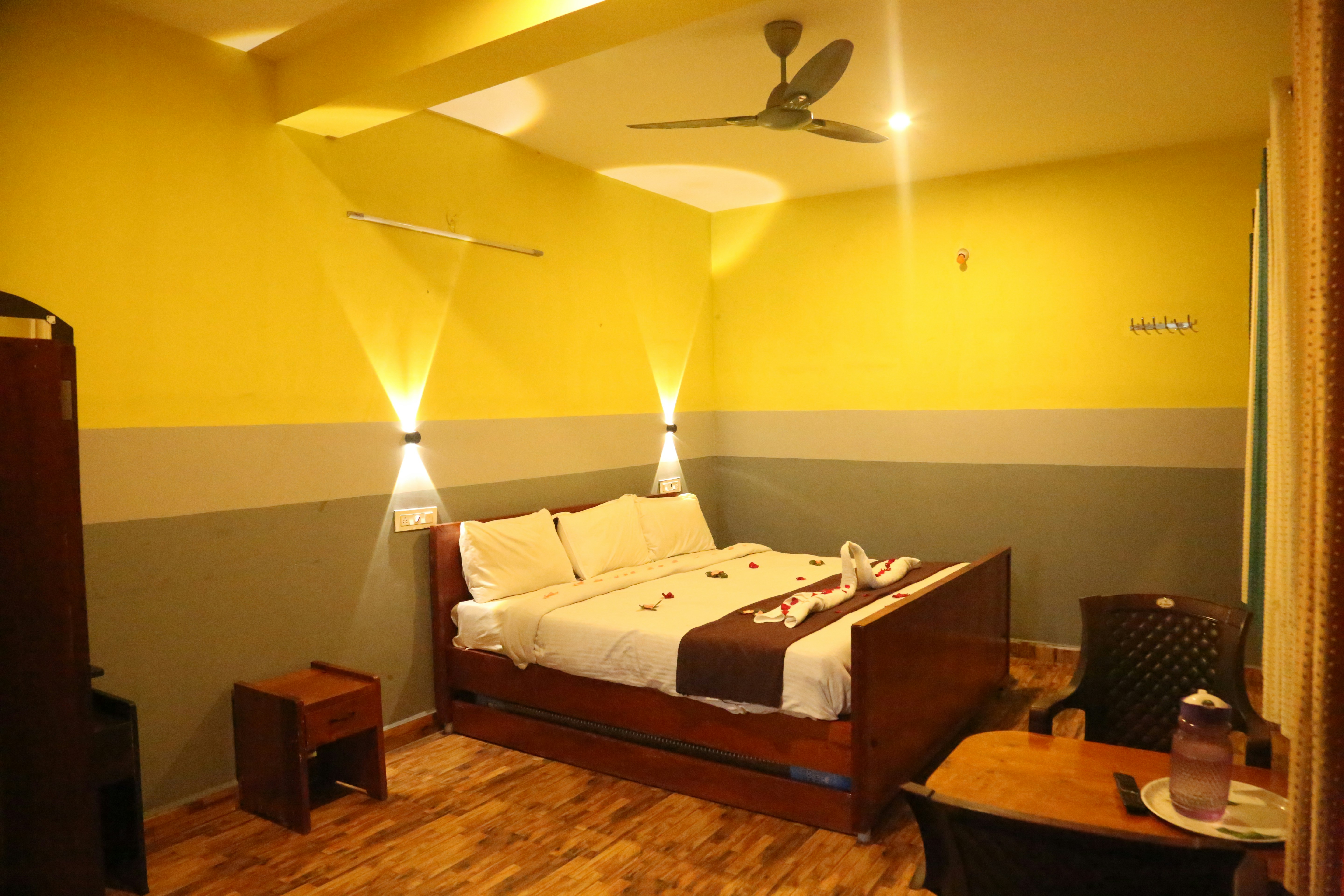 Deluxe hotel room with neatly made double bed, warm lighting, clean white linen, and wooden furniture