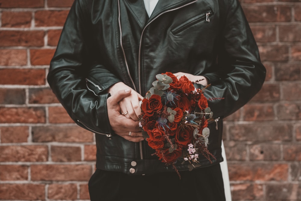 a man in a leather jacket holding a bouquet of roses