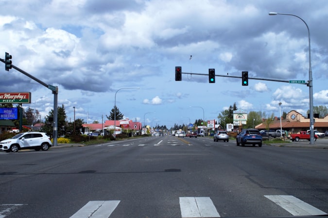 Wide arterial road with a traffic signal and cars, the kind of Las Vegas corridor lined with older single story retail centers