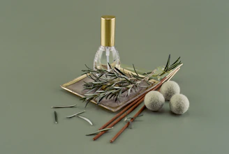 Close-up of a small glass bottle filled with golden natural oil, surrounded by fresh herbs and leaves.
