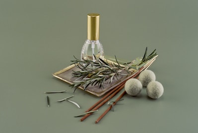 Close-up of a small glass bottle filled with golden Ayurvedic herbal oil surrounded by fresh Indian herbs.
