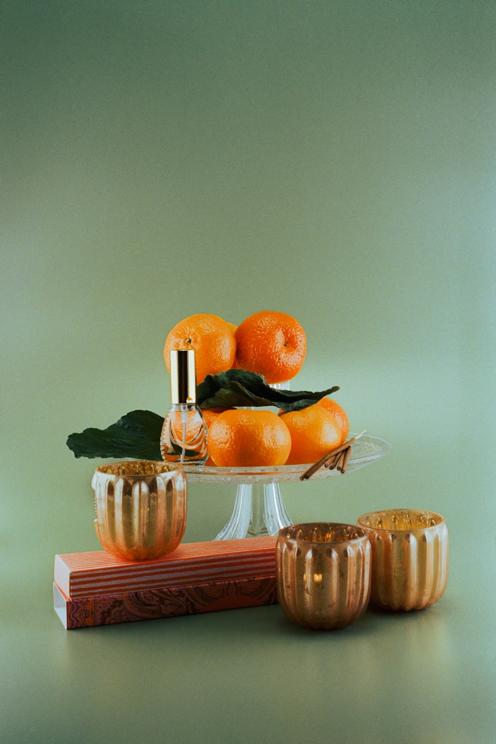 a glass bowl filled with oranges next to a stack of oranges