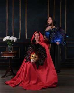 Editorial-style portrait of the duo, showcasing their tailored suits and gold masks with soft champagne accents illuminating their presence.