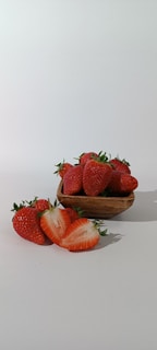 Close-up of a rustic wooden bowl filled with creamy strawberry ice cream topped with fresh strawberries.