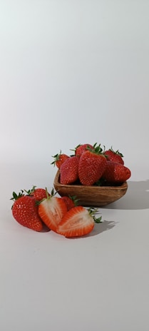 Close-up of a rustic wooden bowl filled with creamy strawberry ice cream topped with fresh strawberries.