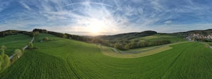 A panoramic view of the farm’s lush fields and cozy animal shelters during sunset.