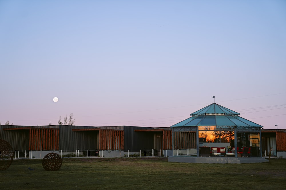 a building with a blue roof and a full moon in the sky