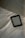 A digital e-reader device is placed on a white, wrinkled fabric surface, possibly a bed. Part of a grey fabric, which could be a blanket or a pillow, is visible in the top right corner. The e-reader screen displays text from an electronic book or document.