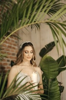 Woman lighting a candle in a serene, softly lit room filled with plants.
