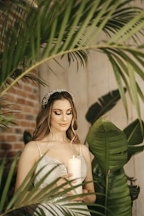 A woman gently holding a glowing candle surrounded by natural herbs.