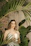 A serene woman sitting peacefully in a softly lit room surrounded by candles and plants.