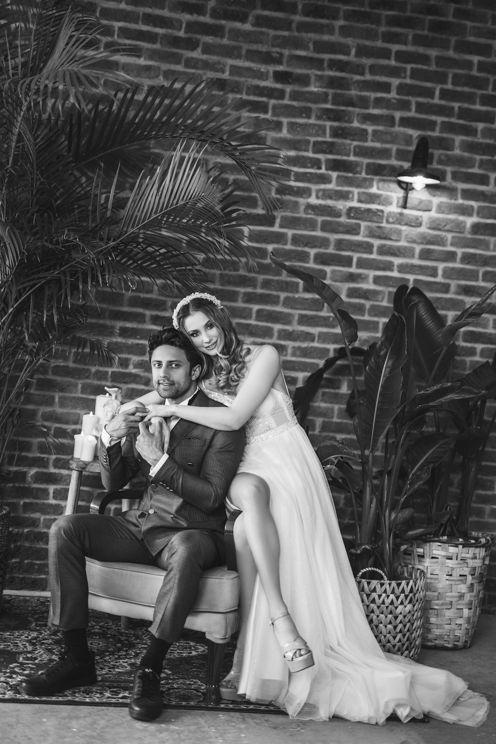 a bride and groom sitting on a bench in front of a brick wall