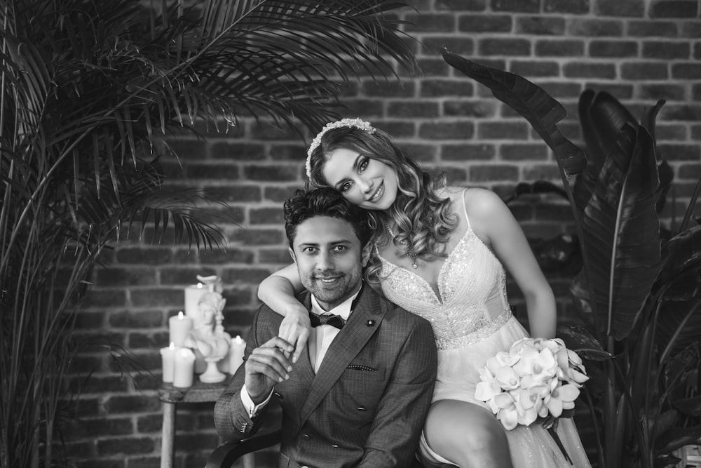 a man and a woman pose for a picture in front of a brick wall