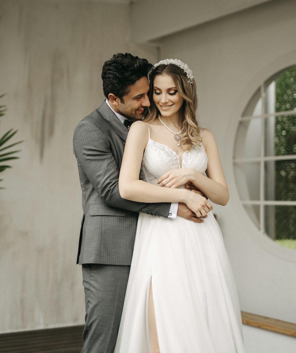 a bride and groom embracing each other in front of a window