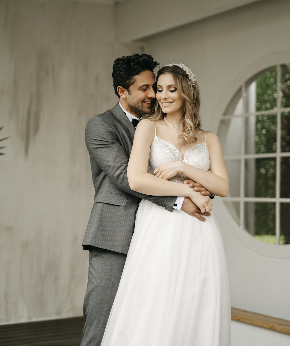 a bride and groom embracing each other in front of a window