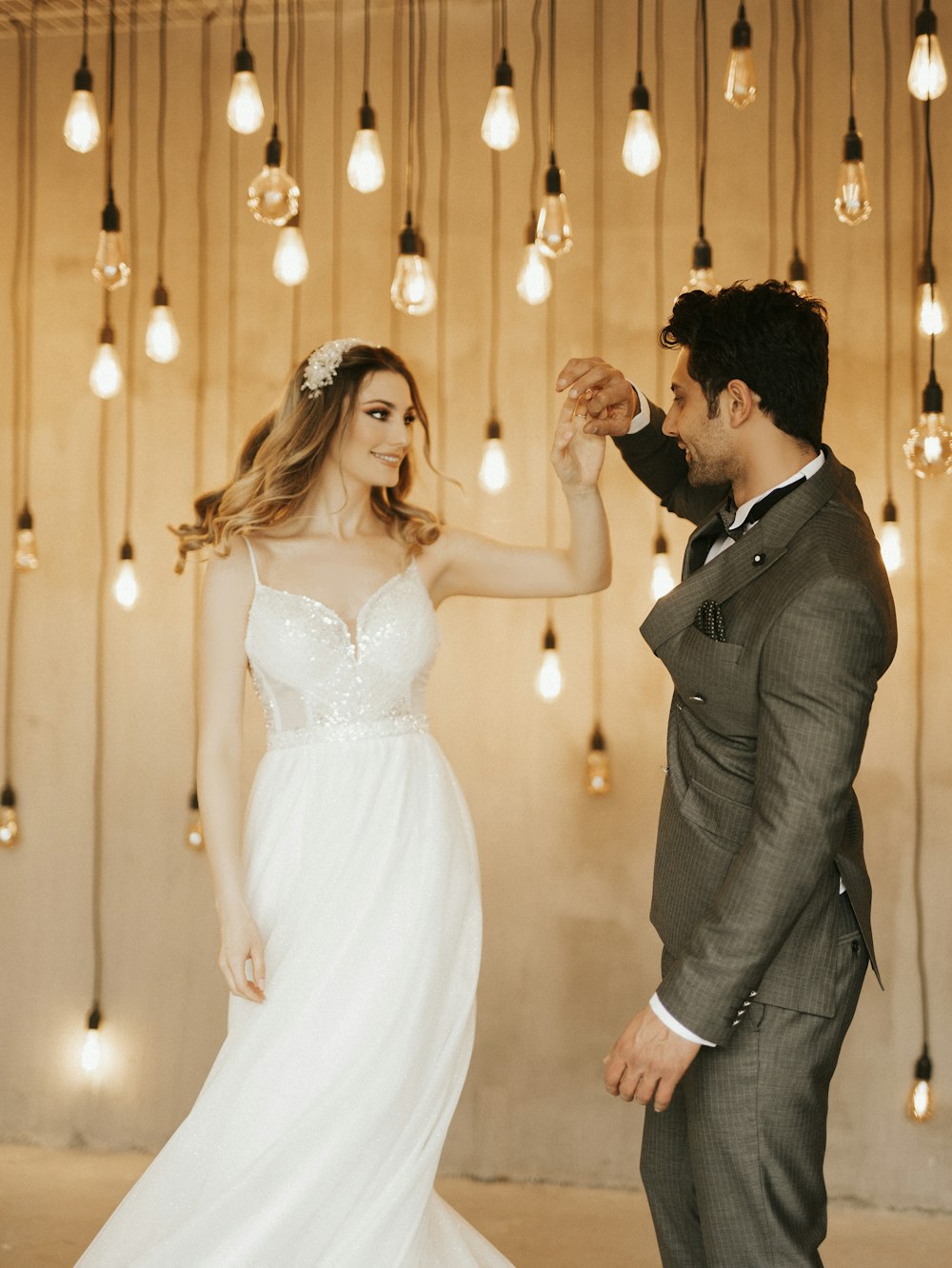 a bride and groom dancing in front of hanging lights