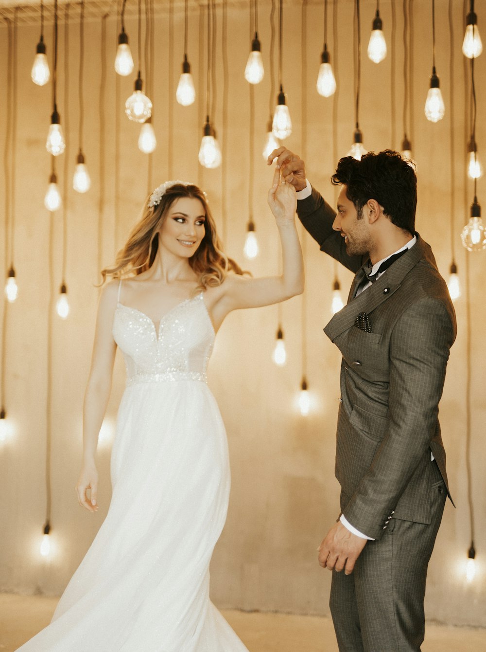 a bride and groom dancing in front of hanging lights