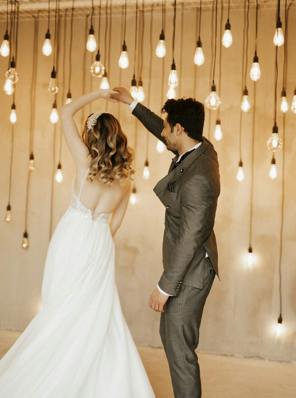 a bride and groom dancing in front of hanging lights