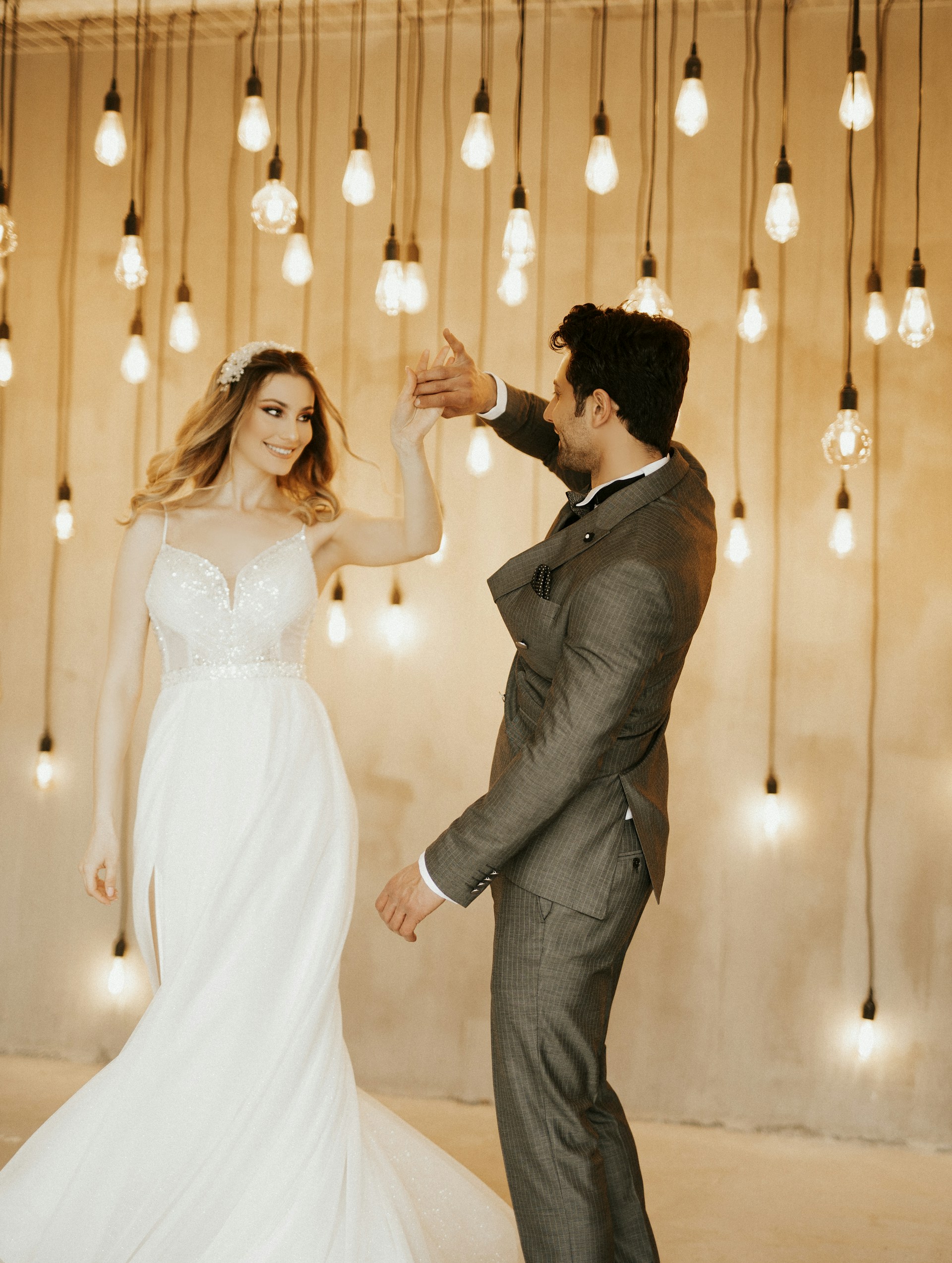 A candid photograph of a couple dancing under soft, romantic lighting at their wedding reception.