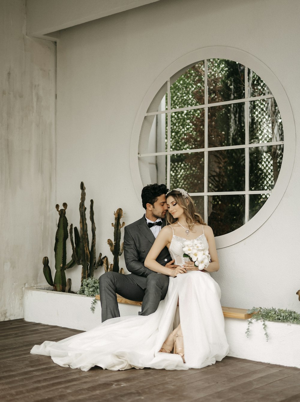 a bride and groom sitting on a bench in front of a circular window