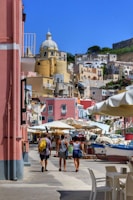 Colorful market street bustling with locals and tourists in a coastal town.