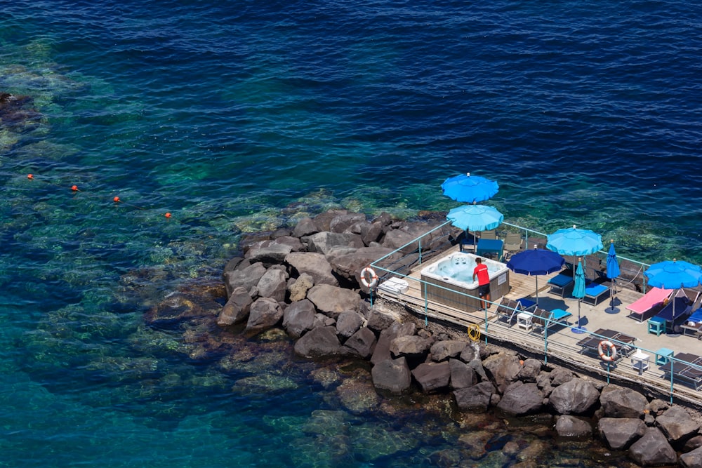 a dock with chairs and umbrellas next to a body of water