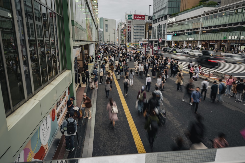 a crowd of people walking down a street next to tall buildings