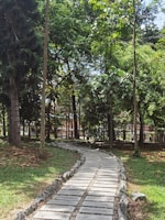 Wide shot of a community park with winding paths, trees, and decorative stone elements.