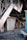 An indoor setting with visible damage and destruction. There are multiple closed, metal roll-up doors, and debris scattered across the floor including broken objects and trash. The area appears abandoned and possibly affected by fire.