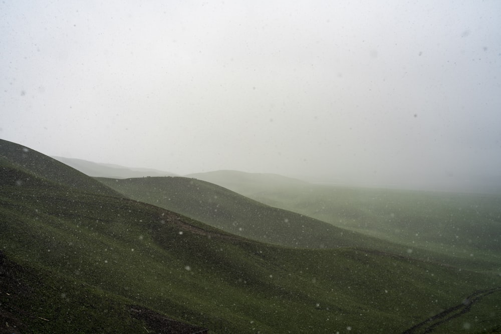 a hill covered in fog and snow on a cloudy day