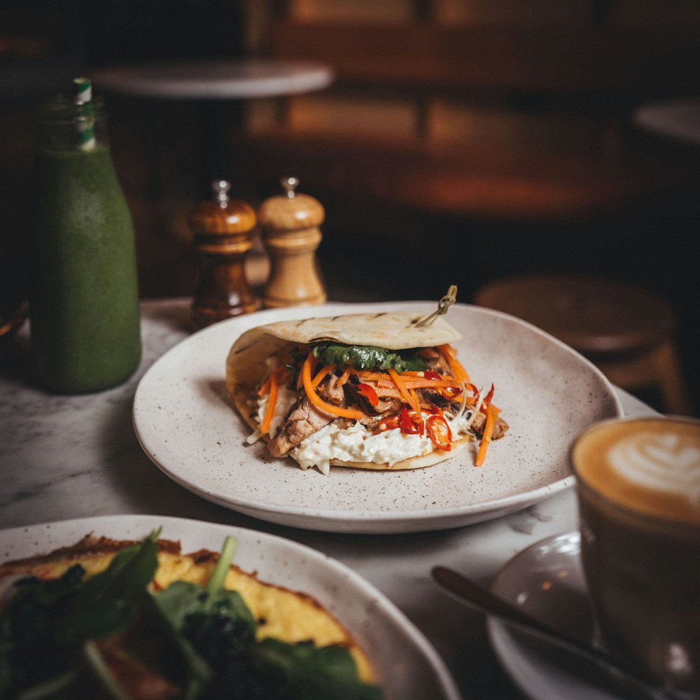 a white plate topped with a sandwich next to a cup of coffee