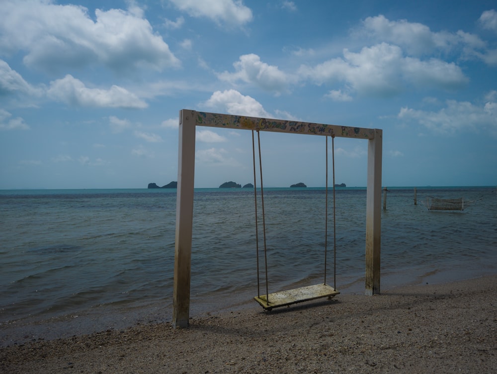 a wooden swing sitting on top of a sandy beach