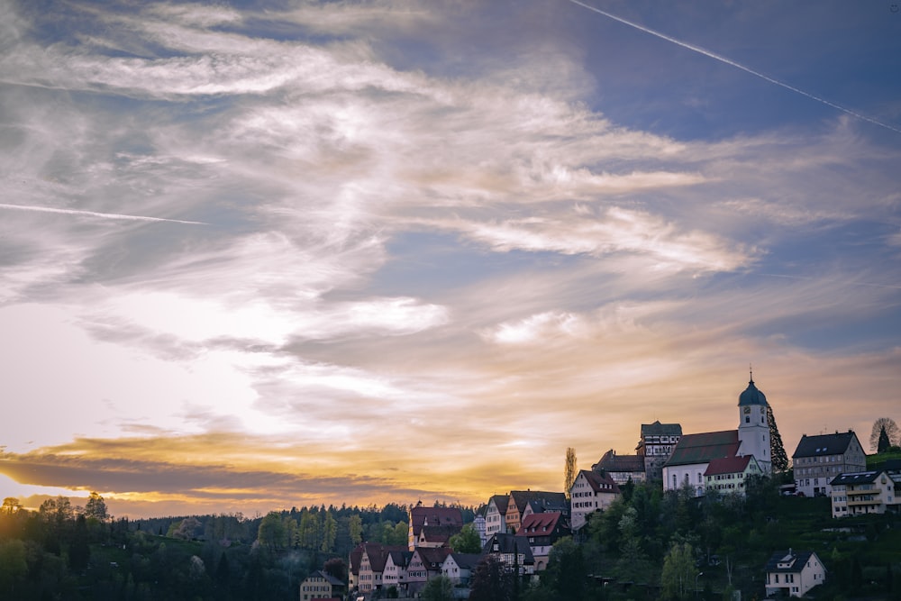a sunset view of a town with a church on a hill
