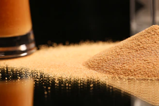 a pile of sand next to a glass of beer