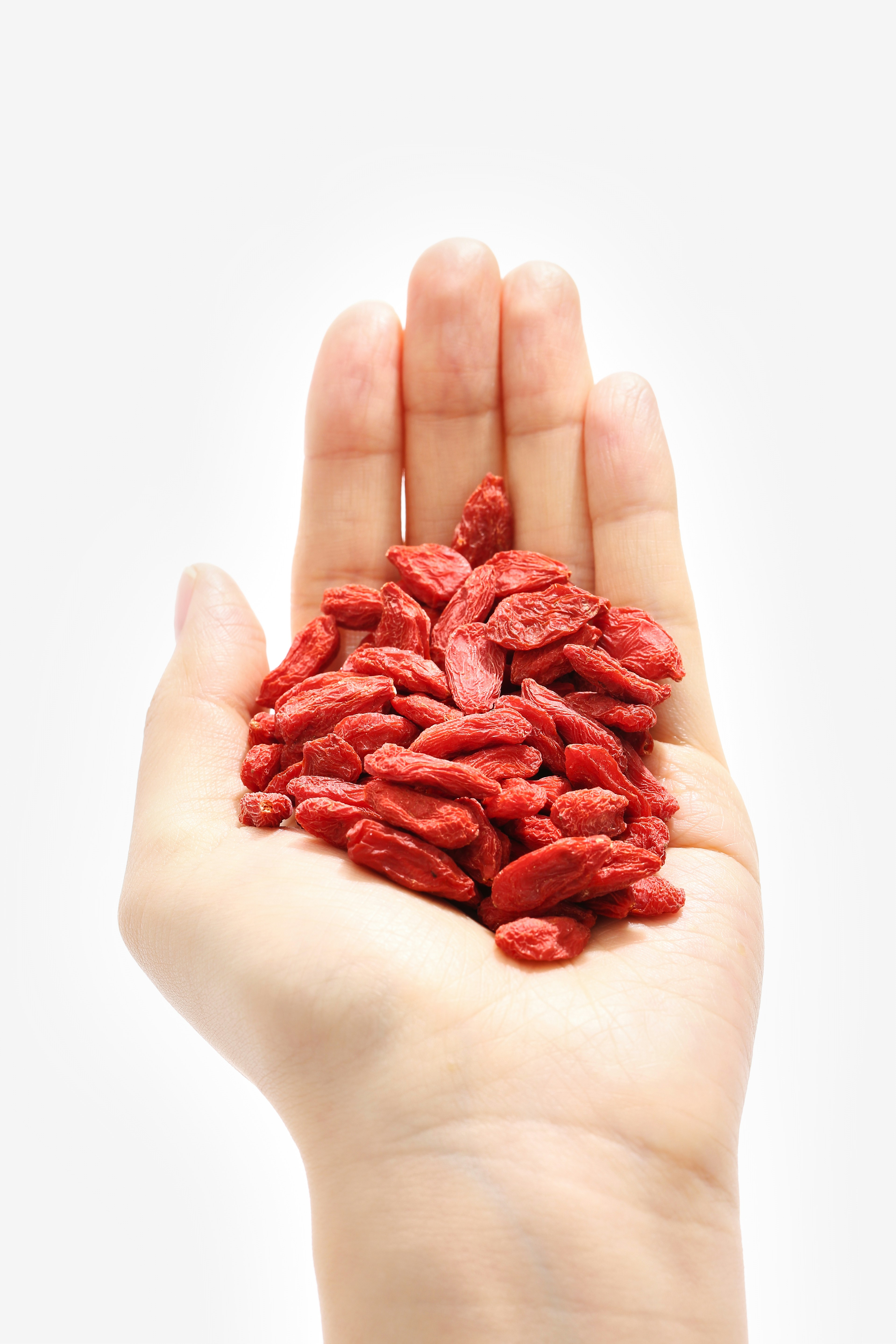 a hand holding a handful of goji berry