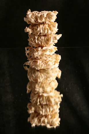 A stack of cream and beige linen fabrics with visible weave patterns, bathed in natural light.