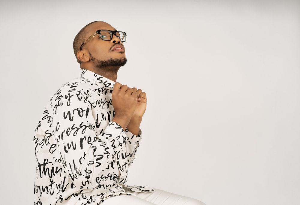 a man with glasses sitting on a stool