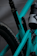 Close-up view of a teal mountain bike frame with visible branding and a mounted water bottle holder. The frame features suspension components and appears to be designed for off-road biking.