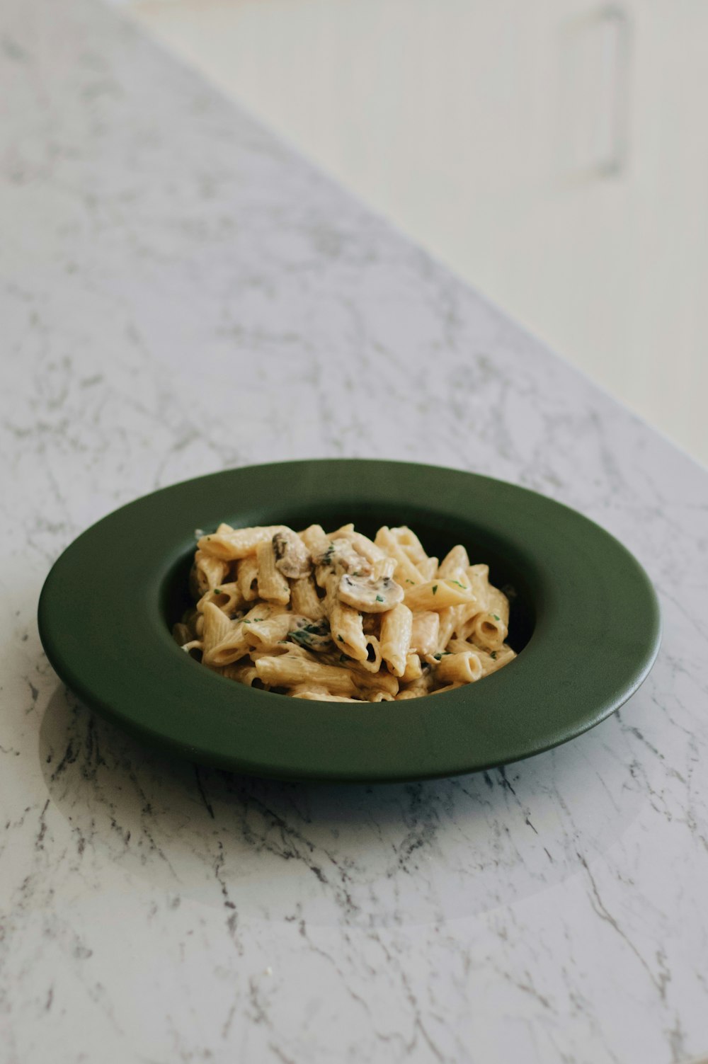 a plate of pasta with mushrooms on a marble table