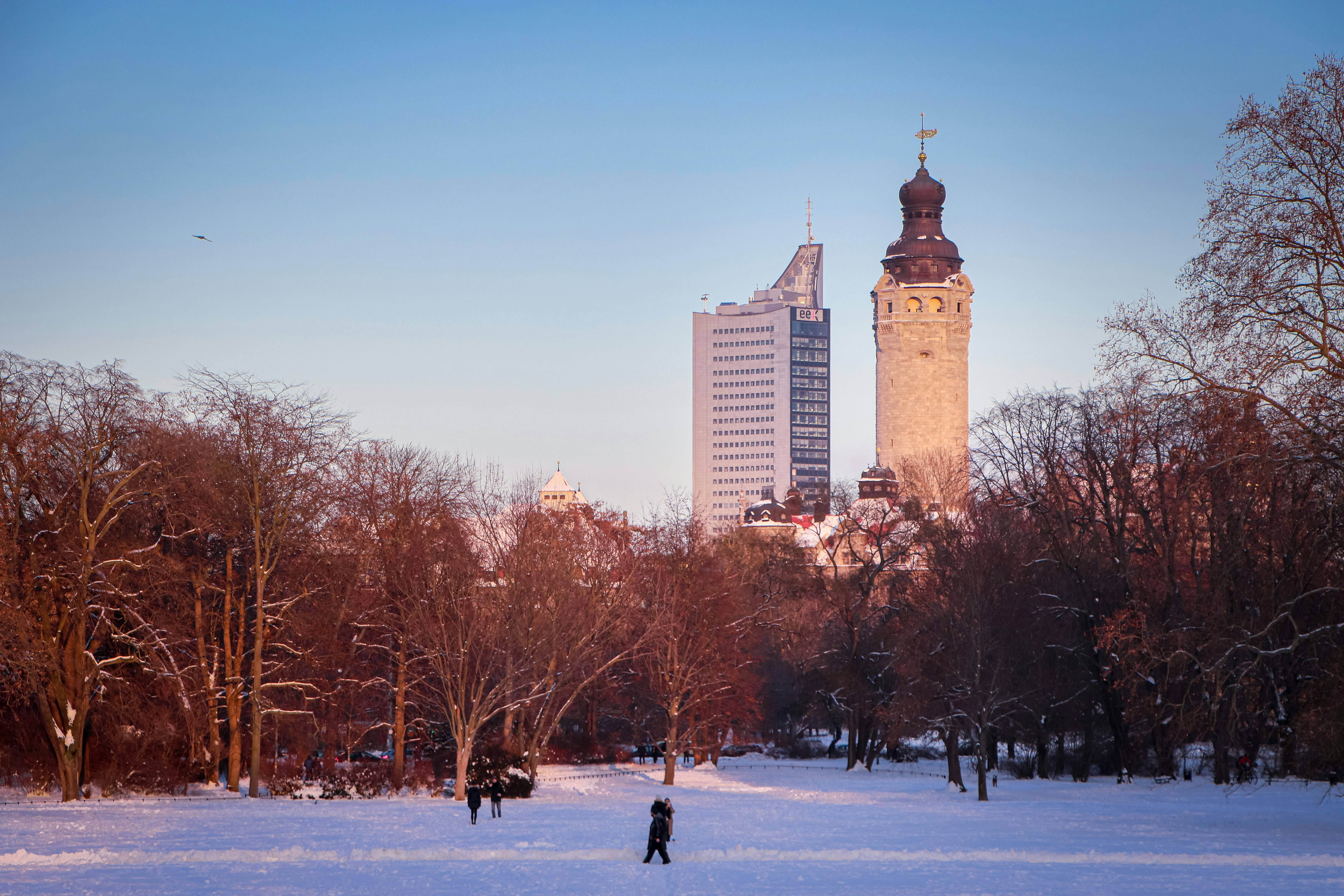 a couple of people walking across a snow covered field